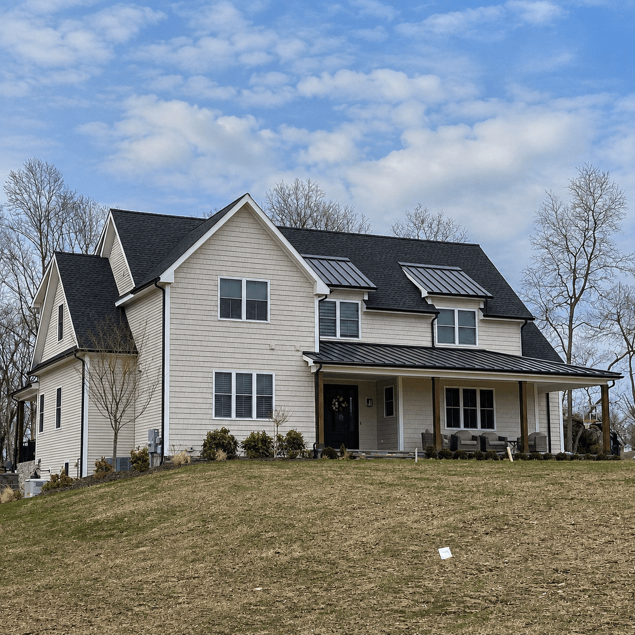A black asphalt-shingle roof across the main gable and roof slopes of a two-story home, above light shake siding.